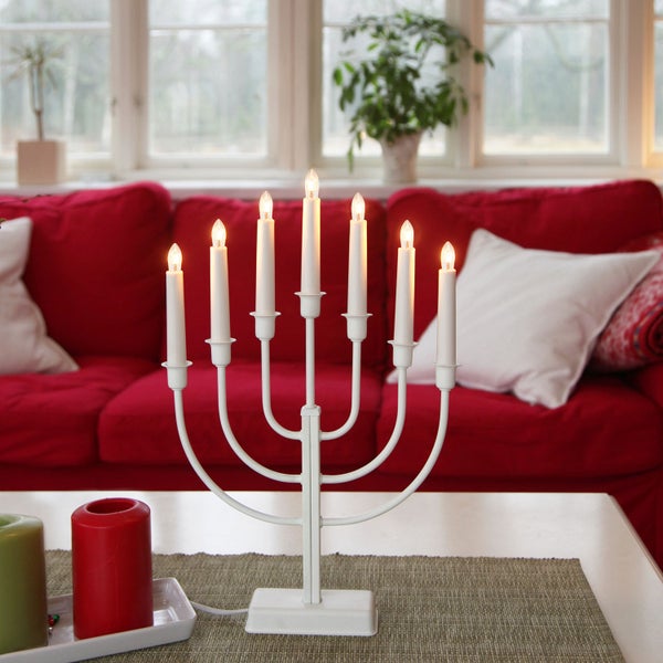 Weißer Lichterbogen mit sieben Lampen auf einem Tisch vor einem roten Sofa.