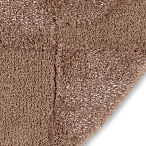 Nahaufnahme eines strukturierten Badteppichs mit geometrischem Muster aus weichem Material in runder Form.