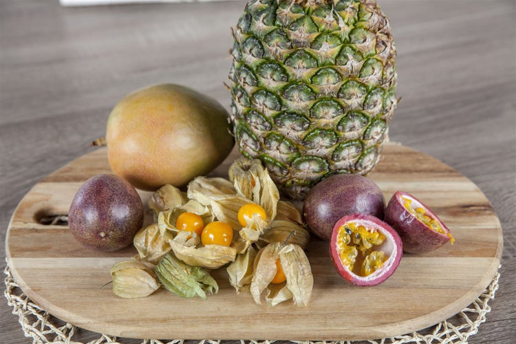 Ananas, Birne, Physalis und Maracuja auf einem Holzbrett