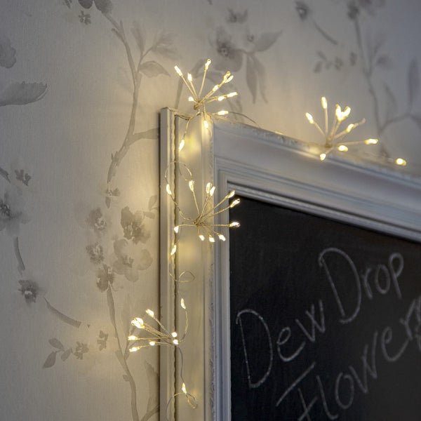 Dekorative Lichterkette mit filigranem Drahtdesign und warmweißem Licht an einer Wand und Tafel