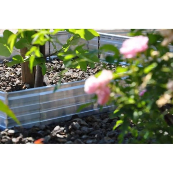 Wellblech Beetumrandung aus Metall in einem Garten mit Pflanzen und dunklem Kies.