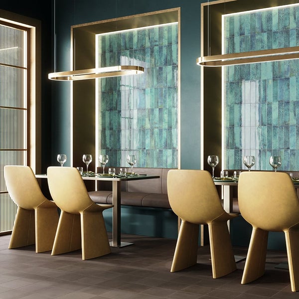 Modernes Esszimmer mit Wandverkleidung aus glänzenden rechteckigen Fliesen, gepolsterten Stühlen und hängenden Leuchten in einem eleganten Raum.