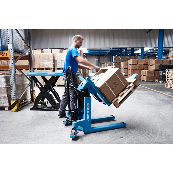 Mitarbeiter bedient einen blauen Palettenkipper in einem Lager zum seitlichen Kippen einer Palette mit Karton.