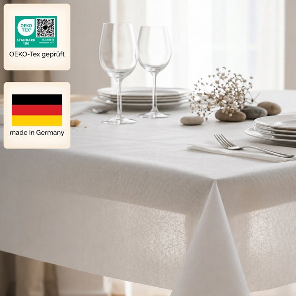 Festlich gedeckter Tisch mit weißer Stofftischdecke, Tellern, Weingläsern und Dekoration. OEKO-TEX zertifiziert und in Deutschland hergestellt.