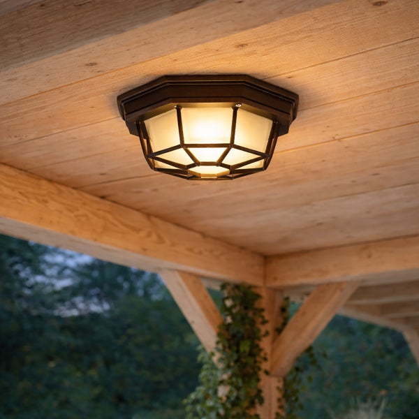 Rustikale Außen-Deckenleuchte mit Metallrahmen und mattem Glas montiert an einer Holzdecke.