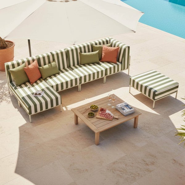 Modernes Garten-Lounge-Set mit grün-weiß gestreiftem Modulsofa, Hocker, Holztisch und großem Sonnenschirm auf einer Steinterrasse am Pool.