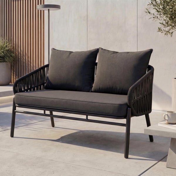 Dunkles Zweisitzer Gartensofa mit Seilbespannung und Metallgestell inklusive Sitzkissen und Rückenkissen auf einer Terrasse.
