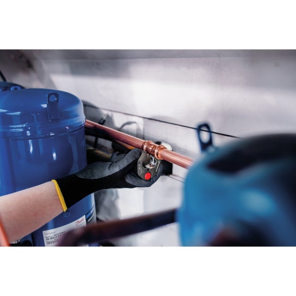 Ein Installateur verwendet ein Werkzeug, um ein Kupferrohr zu verbinden.