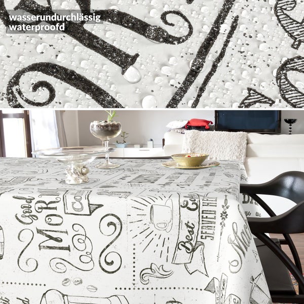 Wasserabweisende Tischdecke mit Kaffeemotiven und Schriftzug Good Morning auf einem Tisch, Detailansicht zeigt Wassertropfen.