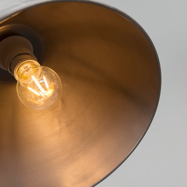 Innenansicht eines Lampenschirms mit einer leuchtenden LED-Filament-Lampe und warmer Reflexion auf der Innenfläche.