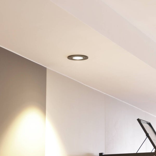 Moderner runder Einbaustrahler an der Decke sorgt für die Beleuchtung in einem hellen, minimalistischen Raum.