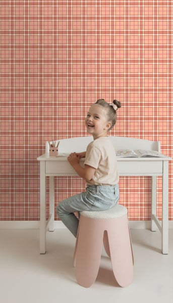 Vliestapete mit Karomuster an der Wand hinter einem Kind an einem weißen Schreibtisch.