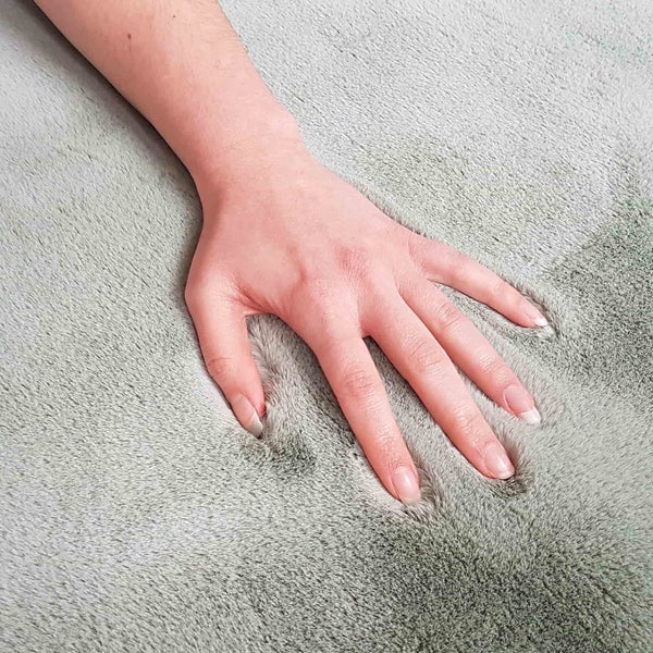 Hand berührt einen Teppich mit hohem Flor