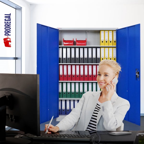 Organisierte Büroszene mit offenem Metallschrank, Regalböden voller Aktenordner und einer arbeitenden Frau am Schreibtisch.