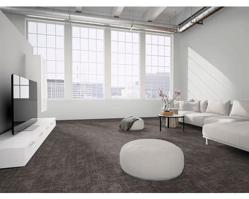 Moderner, heller Wohnraum im Industriestil mit dunkelgrauem, strukturiertem Teppichboden, großen Fenstern und weißem Sofa.