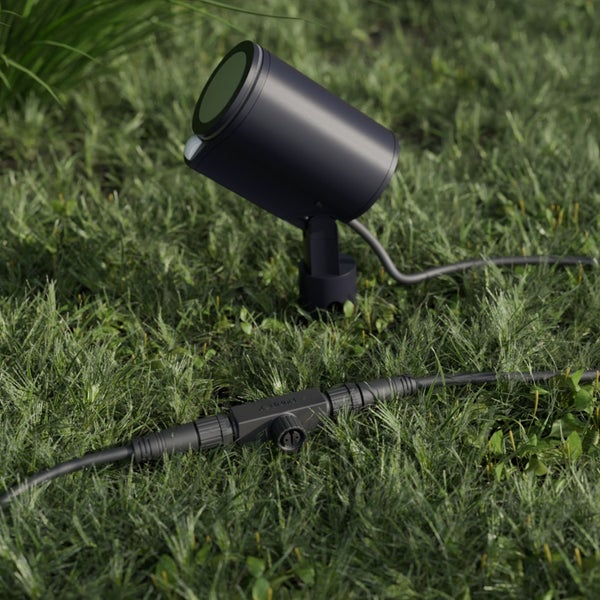 Schwenkbarer LED-Außenstrahler mit Bewegungsmelder im Rasen, inklusive Verbindungskabel.
