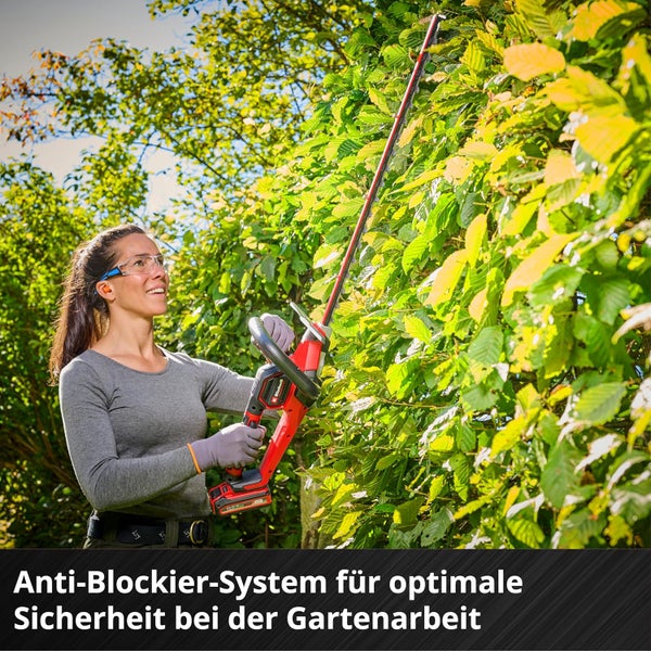 Eine Frau schneidet eine Hecke mit einer Einhell Akku-Heckenschere im Garten.