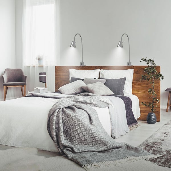 Schlafzimmer mit Holzbett, Kissen, Decken und zwei Leselampen