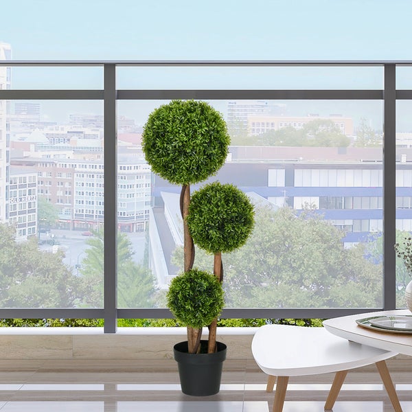 Künstlicher Buchsbaum mit drei Kugeln im schwarzen Topf auf einem modernen Balkon mit Stadtblick.