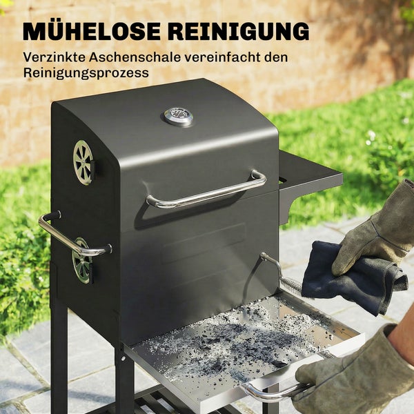 Eine Frau schiebt einen schwarzen Holzkohlegrill mit Rollen und seitlichem Griff in einem Garten.
