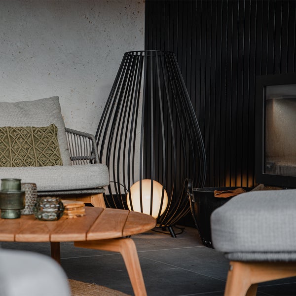 Terrassenszene mit Sessel, Couchtisch und dekorativer Stehleuchte