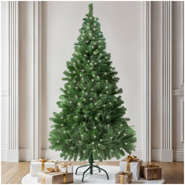 Künstlicher Weihnachtsbaum mit integrierter Lichterkette in einem Raum mit Weihnachtsgeschenken und Holzboden