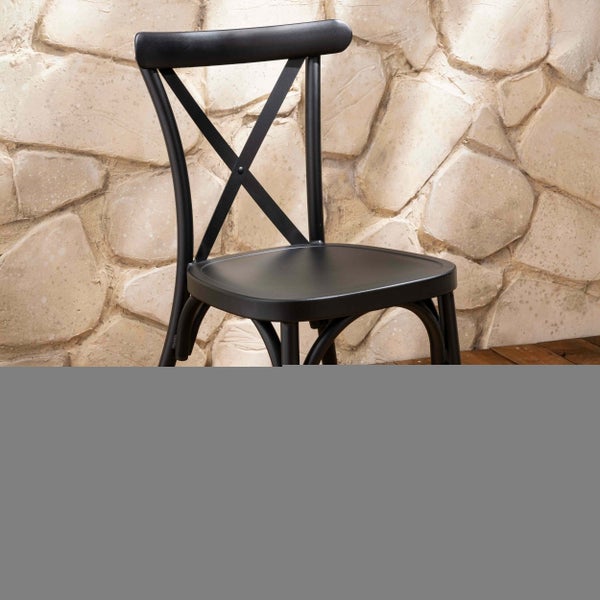 Schwarzer Bistrostuhl mit Kreuzlehne vor einer Steinwand.