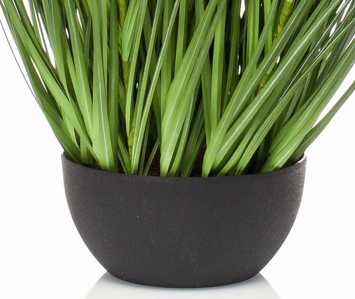 Künstliche Pflanze mit grünen Grashalmen in einem dunklen, runden Pflanztopf.