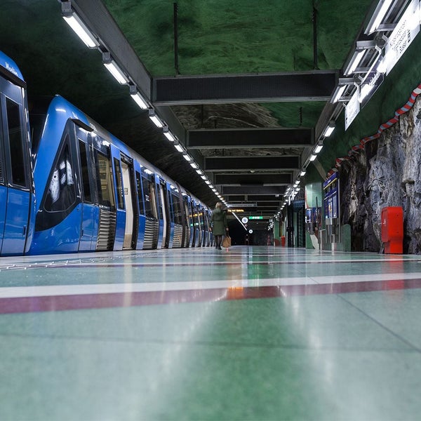 U-Bahn-Station mit blauem Zug und wartenden Personen