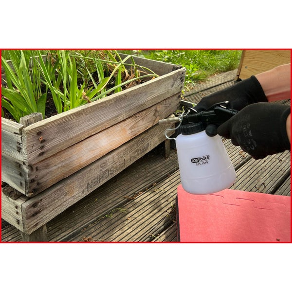 Gartenszene mit Pflanzgefäß, Pflanzenschutzspritze und Handschuhen