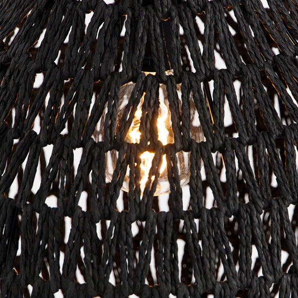 Nahaufnahme eines schwarzen Lampenschirms aus Geflecht mit einer eingeschalteten Glühbirne.