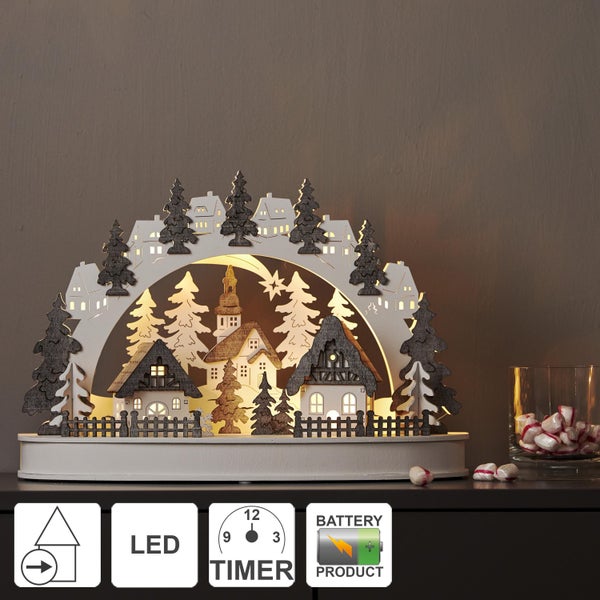 Dekorative beleuchtete Winterdorf-Szene auf einer Kommode