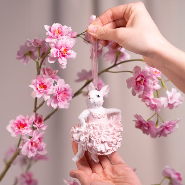 Dekorativer Osterhase als Anhänger mit rosa Kleid und Blütenzweig