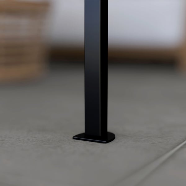 Quadratischer Metallpfosten in Schwarz mit D-förmiger Basis auf Fliesenboden.