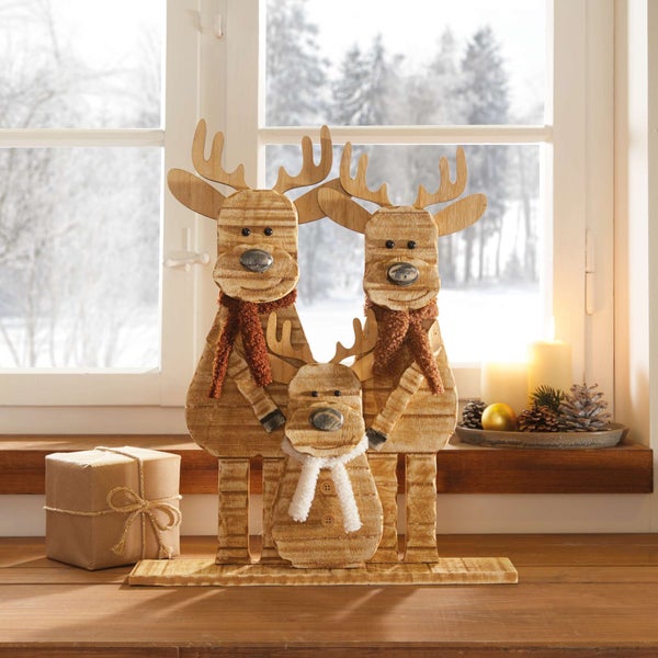 Dekorative Holzfiguren einer Rentierfamilie am Fenster zur Weihnachtszeit.