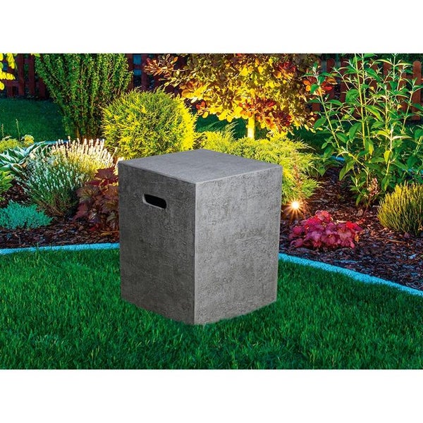 Würfelförmige Gasflaschenverkleidung in Betonoptik auf einer Rasenfläche in einem bepflanzten Garten mit Beleuchtung.
