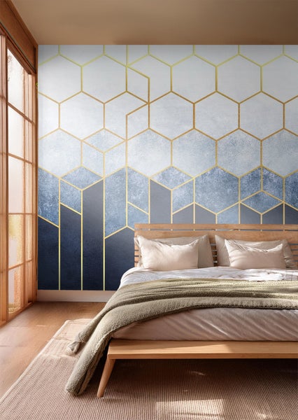 Schlafzimmer mit geometrischer Tapete in Gold und Blautönen über einem Holzbett