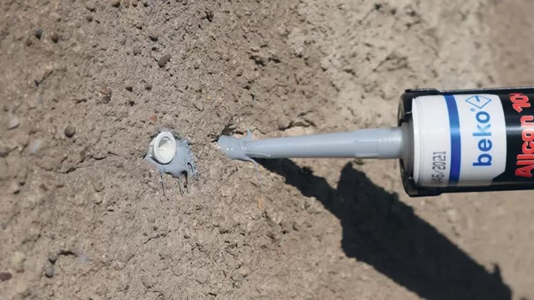 Dichtstoff wird auf Beton aufgetragen. Beko Logo.