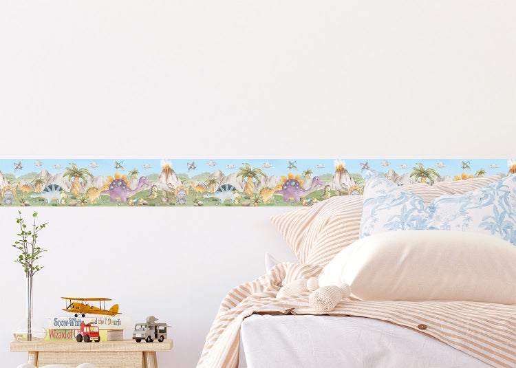 Tapetenborte mit Dinosauriern, Vulkanen und Palmen in einem hellen, organisierten Kinderzimmer an der Wand über einem Bett.