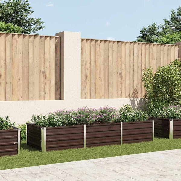Modernes dunkelbraunes Hochbeet mit blühenden Pflanzen auf Rasen vor einer Gartenmauer mit Holzzaun.