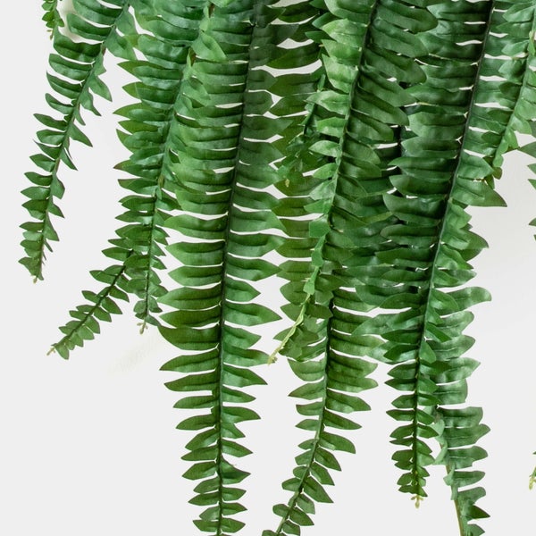 Künstlicher Farn hängend mit grünen Wedeln und fein detaillierten Blättern