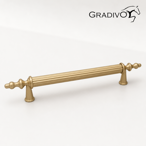 Gradivo Logo. Möbelgriff in Messing-Optik mit geriffeltem Mittelstück und verzierten Enden.