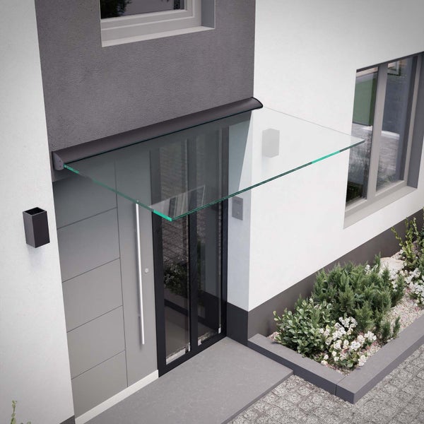 Modernes Vordach aus Klarglas über einer grauen Haustür an einer weiß-grauen Hauswand mit bepflanztem Beet.