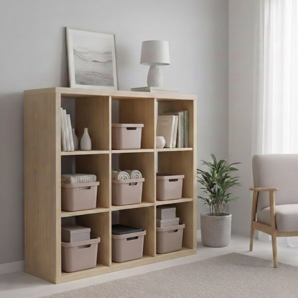 Ein quadratisches Regal aus Holz mit neun offenen Fächern, dekoriert mit Aufbewahrungsboxen, Büchern und einer Lampe in einem hellen Wohnraum.