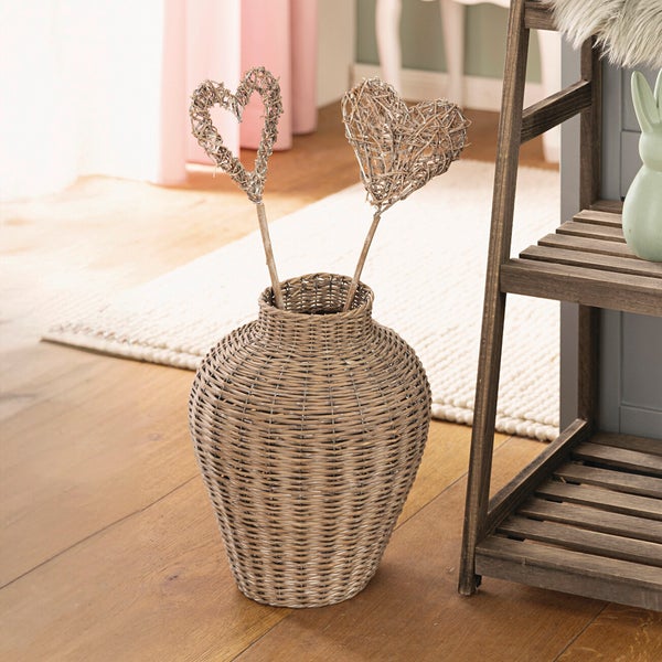 Dekorative Weidenherzen in einer geflochtenen Vase neben einem Holzregal