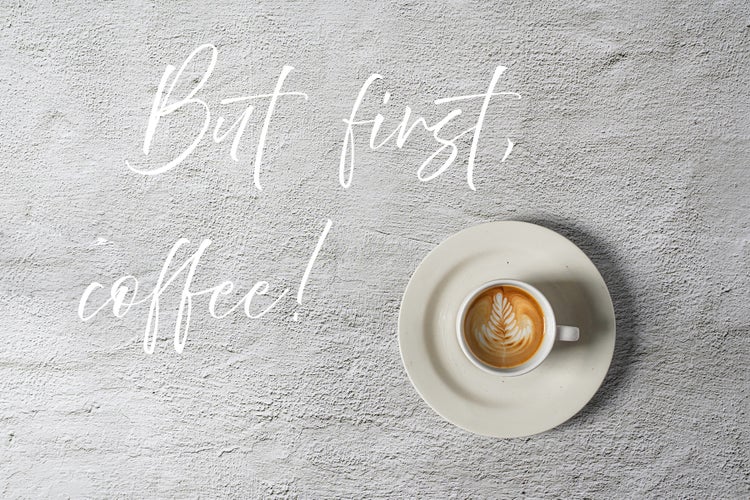 Kaffeetasse mit Latte Art auf Untertasse und der Schriftzug Zuerst Kaffee