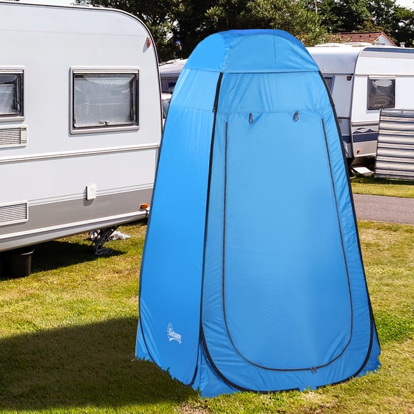 Blaues Pop-up-Duschzelt und Umkleidezelt auf einer Rasenfläche neben einem Wohnwagen auf einem Campingplatz.