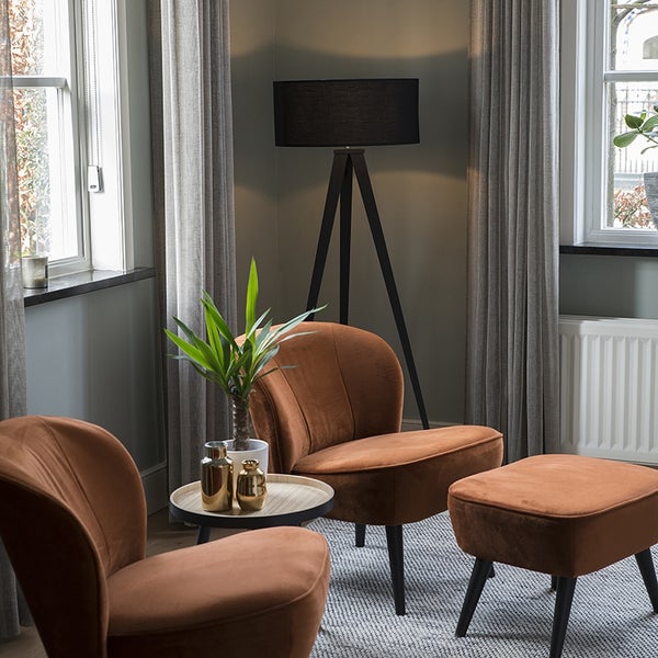 Wohnzimmer mit zwei Sesseln, einem Hocker, einem Beistelltisch und einer Stehlampe.