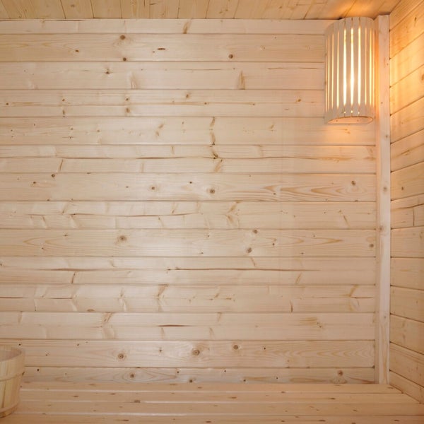 Innenansicht einer Sauna mit Holzwandverkleidung aus Profilholz und einer indirekten Saunalampe mit Holzschirm.