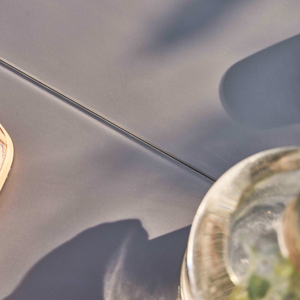 Nahaufnahme einer grauen strukturierten Oberfläche eines Gartenmöbelstücks mit einer schmalen Fuge und Schattenwurf